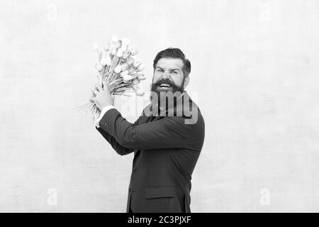 Homme barbu en colère avec des fleurs. Fêtez le printemps. Échec de la date. Irritée, l'homme barbu agacé avec bouquet de tulipes. Concept déçu. Date d'échec. Des vacances de haine. Journée pour femme. 8 Mars. Banque D'Images