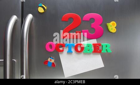 Octobre 23 date calendaire faite avec des lettres magnétiques en plastique tenant une note de papier graphique sur le réfrigérateur de porte Banque D'Images