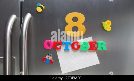 Octobre 8 date calendaire faite avec des lettres magnétiques en plastique tenant une note de papier graphique sur le réfrigérateur de porte Banque D'Images