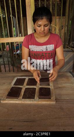 Puerto Quito, Pichincha / Equateur - août 17 2017: Jeune femme latine tirant les blocs de chocolat des moules en bois Banque D'Images