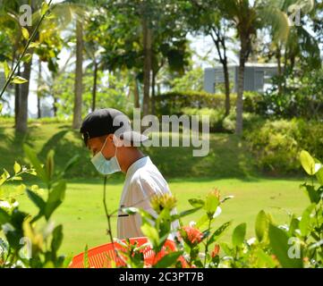 Boao,Qionghai,Hainan, Chine - Mai 30 2020: Un homme travaillant dans le jardin avec le masque sur le jour ensoleillé pendant l'heure COVID-19 Banque D'Images