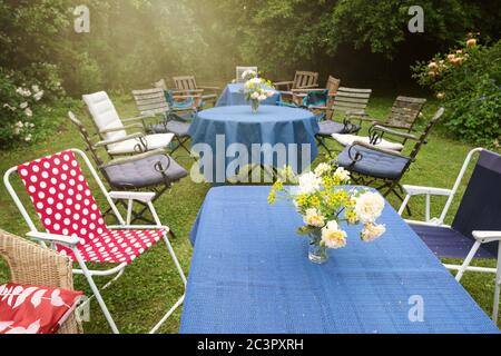 Jardin informel de fête avec des tables, des nappes bleues et des chaises différentes dans une arrière-cour de campagne, foyer choisi Banque D'Images