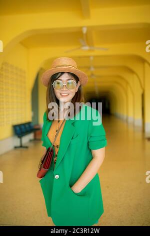 visage souriant et ensanglant d'une femme asiatique portant un costume vert sur fond jaune Banque D'Images