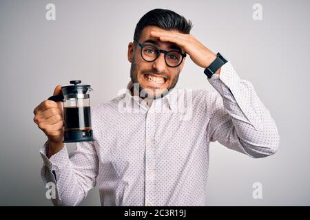 Jeune homme beau faisant du café en utilisant la presse française machine à café sur un fond isolé stressé avec la main sur la tête, choqué par la honte et la surprise f Banque D'Images