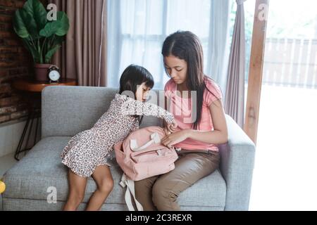 la sœur aînée aide à préparer la sœur avant de retourner à l'école Banque D'Images