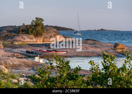 Un kayakiste se détendant dans les rochers de l'archipel de Kirkkonummi, Finlande Banque D'Images