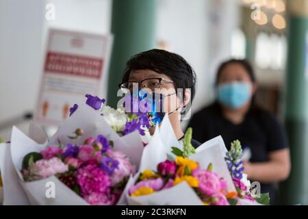 Wilson Yang (l) et Nikki Cha, du jardin de Blong, livrent des fleurs au marché de Pike place à Seattle, à mesure que les restrictions en cas de pandémie du coronavirus sont assouplies le dimanche 21 juin 2020. King County est passé à la phase 2 vendredi dans le cadre du plan de réouverture Safe Start du gouverneur Jay Inglee, ce qui a permis d'augmenter la capacité des entreprises de détail à 30 % de l'occupation maximale du bâtiment. Banque D'Images