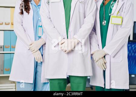 Image rognée des travailleurs médicaux en blouses blanches et gants en caoutchouc dans le hall d'hôpital Banque D'Images