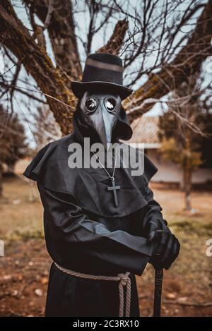 Médecin de la peste avec une canne et une garbe sombre classique avec une croix Banque D'Images