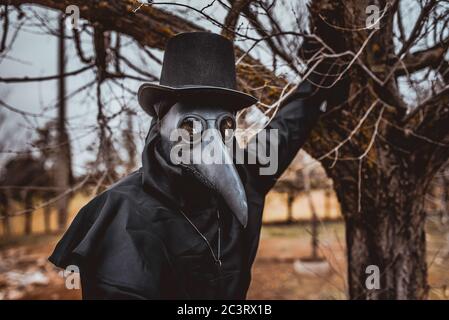 Médecin de la peste avec une canne et une garbe sombre classique avec une croix Banque D'Images