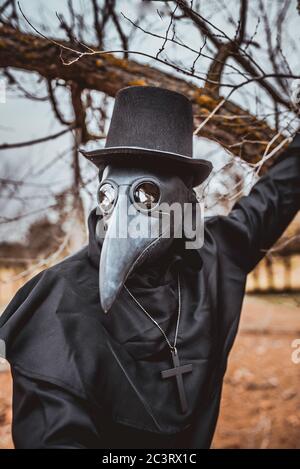 Médecin de la peste avec une canne et une garbe sombre classique avec une croix Banque D'Images