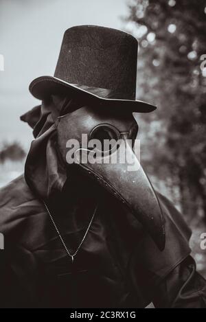 Médecin de la peste avec une canne et une garbe sombre classique avec une croix Banque D'Images