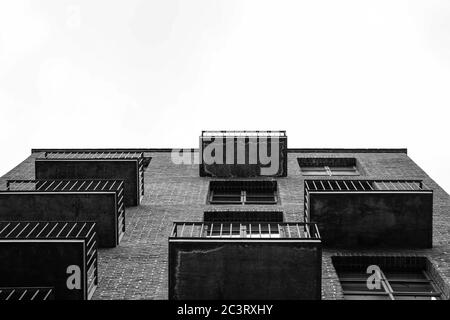 Photo en niveaux de gris d'une façade de bâtiment en brique sur un blanc fond ciel Banque D'Images