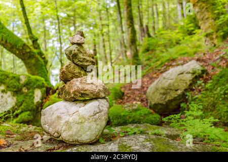Résumé tour zen en pierre dans une forêt verte, de la mousse et des rochers sous les arbres et la lumière du soleil Banque D'Images