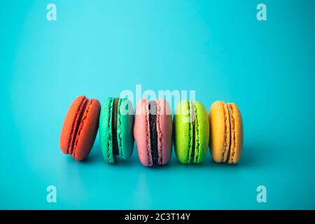 Biscuits de macaron de couleur (macarons) sur fond bleu. Pâtisseries, desserts et bonbons de fête. Fond de cuisson Banque D'Images