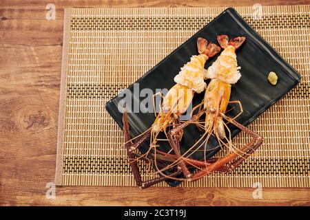 Homards à la langouste cuits servis sur une assiette noire avec un morceau de pâte d'ail Banque D'Images