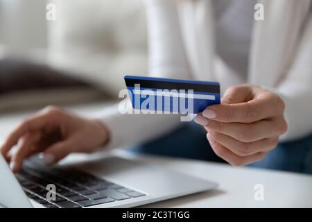 Gros plan image femme utilisant ordinateur portable tenant la carte de crédit effectue le paiement Banque D'Images