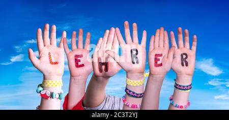 Les mains des enfants construire le mot Lehrer signifie enseignant, ciel bleu Banque D'Images