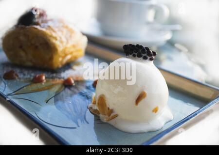 Boule de glace appétissante avec blackberry et strudel de pomme sur une table dans un café. Gros plan d'un délicieux dessert décoré avec soin. Bba flou Banque D'Images