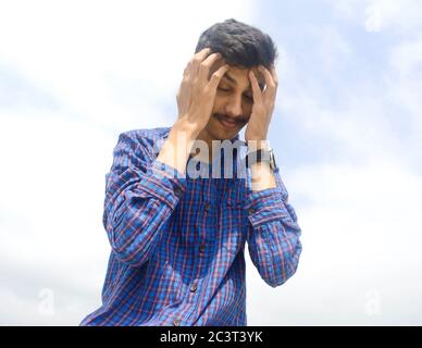 Jeune homme souffrant de maux de tête forts ou de fond migrant.Sky. Banque D'Images