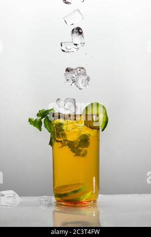 Verre de thé glacé au citron avec feuilles de menthe poivrée et glaçons. Isolé sur fond blanc. Banque D'Images