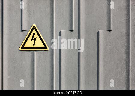 Signe de haute tension sur une surface métallique grise. Symbole de danger électrique sur un panneau d'avertissement sur fond gris Banque D'Images