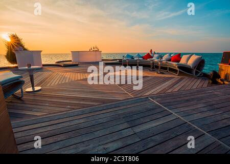 Détendez-vous dans un espace salon près de la mer calme dans un hôtel de luxe sur les rives de l'océan Indien. Vue sur le coucher du soleil dans un complexe tropical Banque D'Images