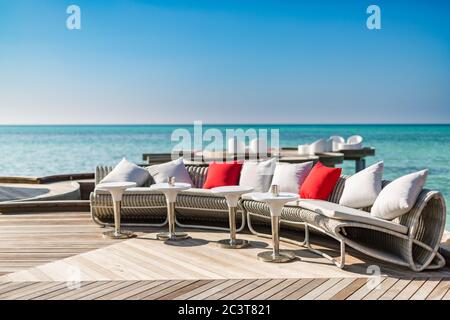 Chaises longues sur la plage des Maldives. Détendez-vous dans un espace salon près de la piscine dans un hôtel de luxe sur les rives de l'océan Indien Banque D'Images