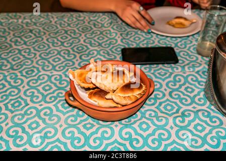 Femme mangeant des empanadas, plat typique de l'Argentine, artisan en céramique avec la poterie indigène similaire avec des empanadas frais maison (detai Banque D'Images