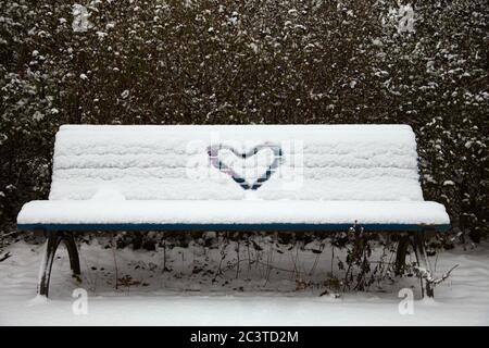 Cœur peint dans la neige sur un banc enneigé Banque D'Images