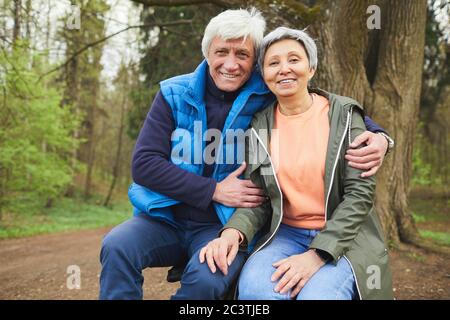 Portrait d'un couple senior actif souriant regardant avec joie l'appareil photo tout en posant pendant la randonnée dans la forêt d'automne, espace de copie Banque D'Images