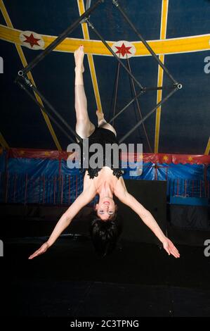 La femme Aerialist acrobat se produit dans les airs sur un trapèze dans une tente de cirque Banque D'Images