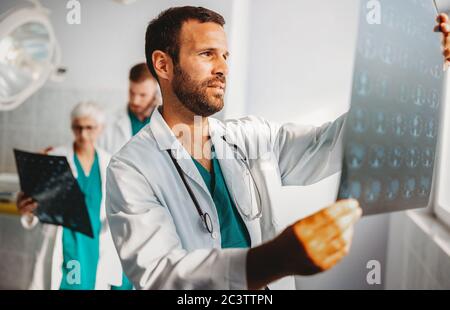 Les médecins de l'équipe médicale qui vérifient les résultats de radiographie à l'hôpital Banque D'Images