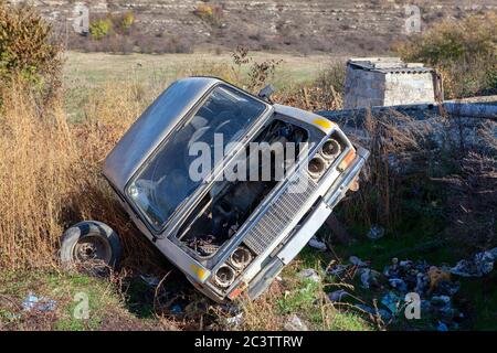 la vieille voiture est jetée dans les ordures. Automobile abandonnée à la benne Banque D'Images