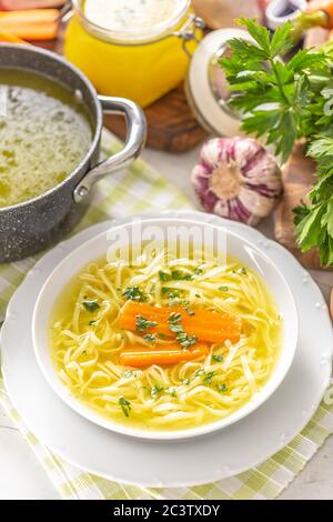 Bouillon de soupe de poulet dans une assiette de carottes oignon céleri herbes ail et légumes frais Banque D'Images