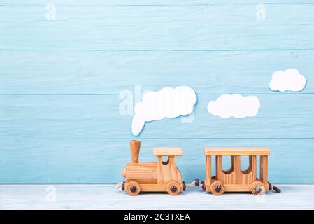 Arrière-plan pour enfants, train de jouets rétro en bois avec vapeur sur fond bleu en bois Banque D'Images