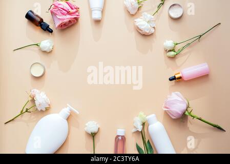 Cosmétiques à base d'ingrédients naturels et extraits de fleurs et de roses sur fond beige avec maquette et espace de copie. Banque D'Images