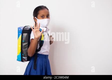 Bonne fille de retour à l'école après Covid-19 lock-down. Retour à l'école concept en signe de bien-être aux parents. Banque D'Images