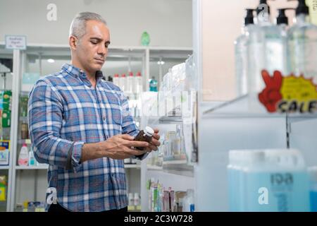 Les hommes lisant l'étiquette de la bouteille de médicament. Banque D'Images