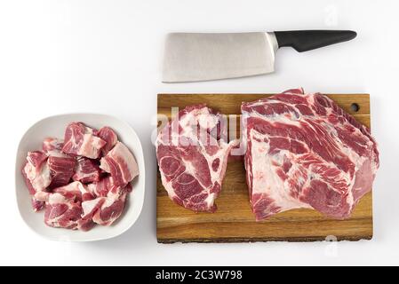 Côtelettes de porc crues dans une palte blanche, et viande de porc crue sur une planche à découper en bois. Espace de copie. Banque D'Images