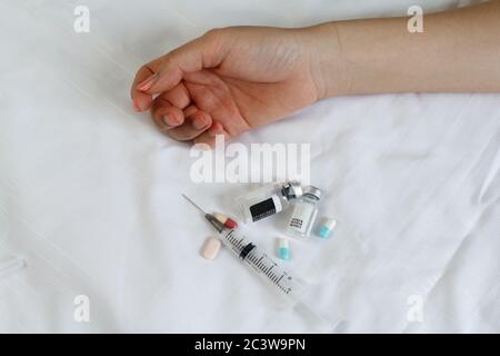 Concept de drogue - main passive sur le lit. Pilules et injection Banque D'Images