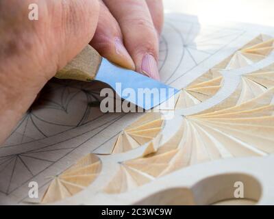 Couteau pour sculpeuse crée un motif géométrique sur une planche en bois. Banque D'Images