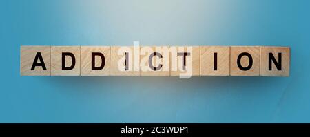 MOT DE DÉPENDANCE sur des cubes en bois sur fond de bois sombre Banque D'Images