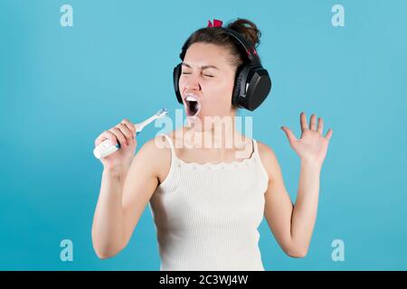 elle brosse ses dents dans un casque et chante dans le brosse comme un microphone Banque D'Images