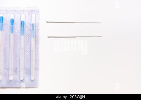 Deux aiguilles d'acupuncture à côté d'un paquet avec des aiguilles sur une table blanche avec un espace de copie Banque D'Images