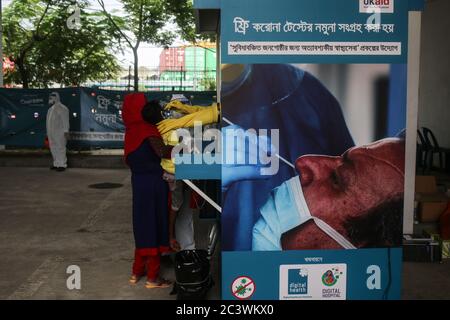 Dhaka, Dhaka, Bangladesh. 22 juin 2020. Une femme tenant son garçon qui a eu de nouveaux symptômes du coronavirus (COVID-19), donne un échantillon dans un stand de collecte d'échantillons à tester à Dhaka. Crédit: Md Rakibul Hasan/ZUMA Wire/Alay Live News Banque D'Images