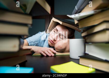 Une jeune fille étudiante s'est endormi sur un livre se cachant derrière un autre livre Banque D'Images