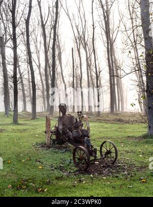 Homme de sculpture métallique brumeux dans un véhicule parmi une bosquet de peupliers. Banque D'Images