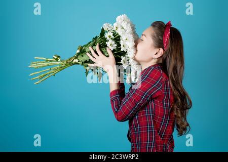 une fille dans une chemise rouge sniffs un grand bouquet de chrysanthèmes blancs Banque D'Images