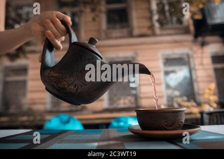 main féminine avec bouilloire à thé vintage et tasse à l'extérieur au coucher du soleil Banque D'Images